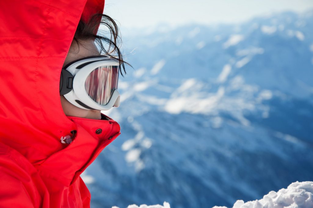 Close-up of skiing girl with goggles, on mountains background